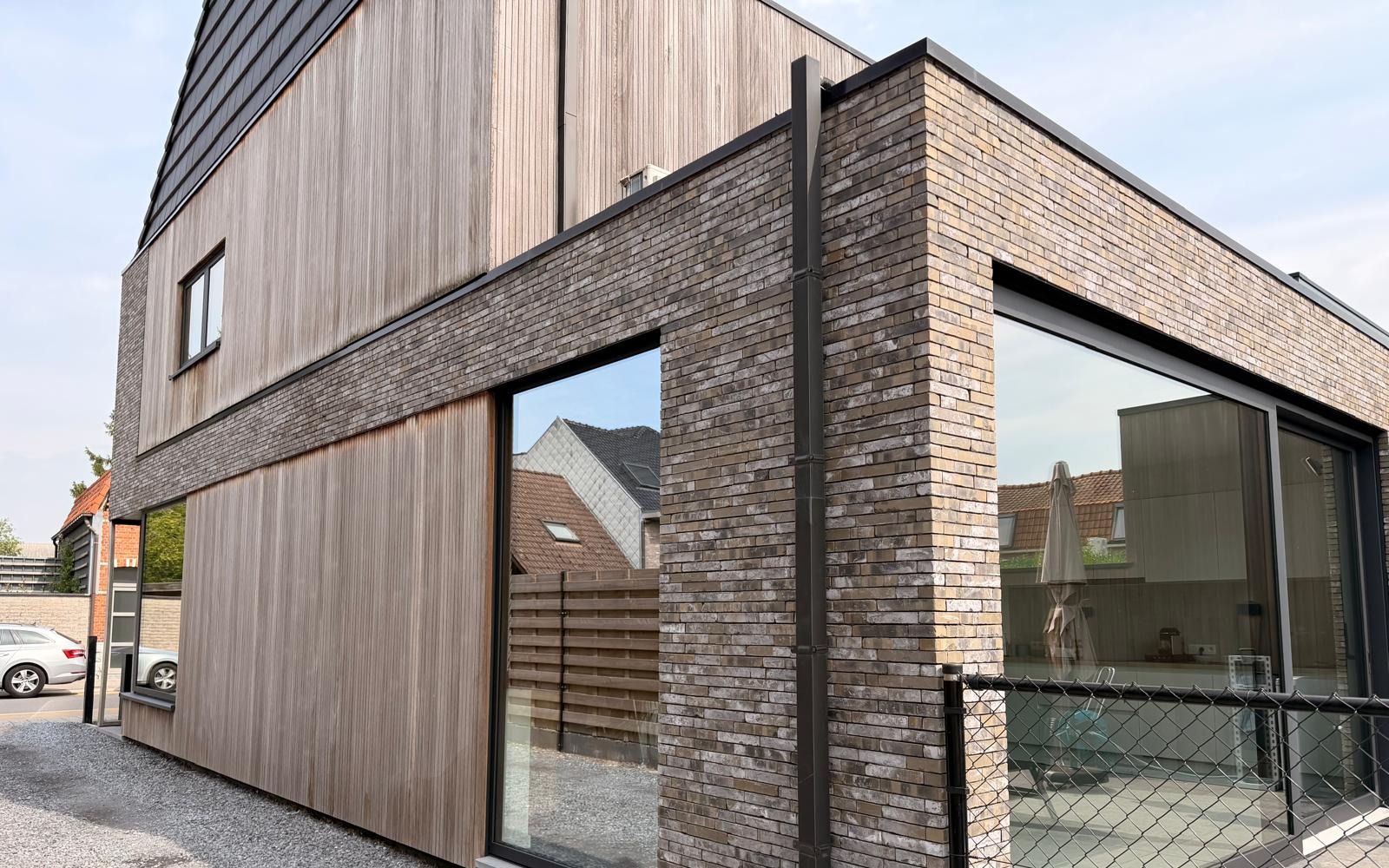 Moderne woning met houten gevelbekleding en grote glaspartijen, ramen gewassen